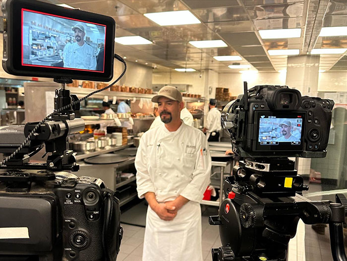 A chef being interviewed with cameras in a kitchen