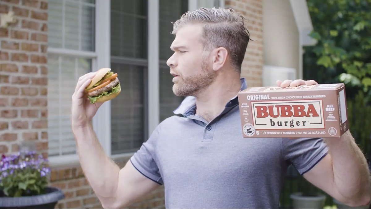 A man holding an original BUBBA Burger box and a grilled burger